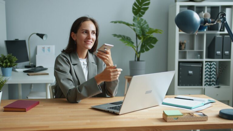 Professionnelle utilisant un smartphone et un ordinateur pour gérer les demandes clients